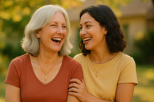 Mother and daughter laughing together outdoors, wearing simple jewelry.