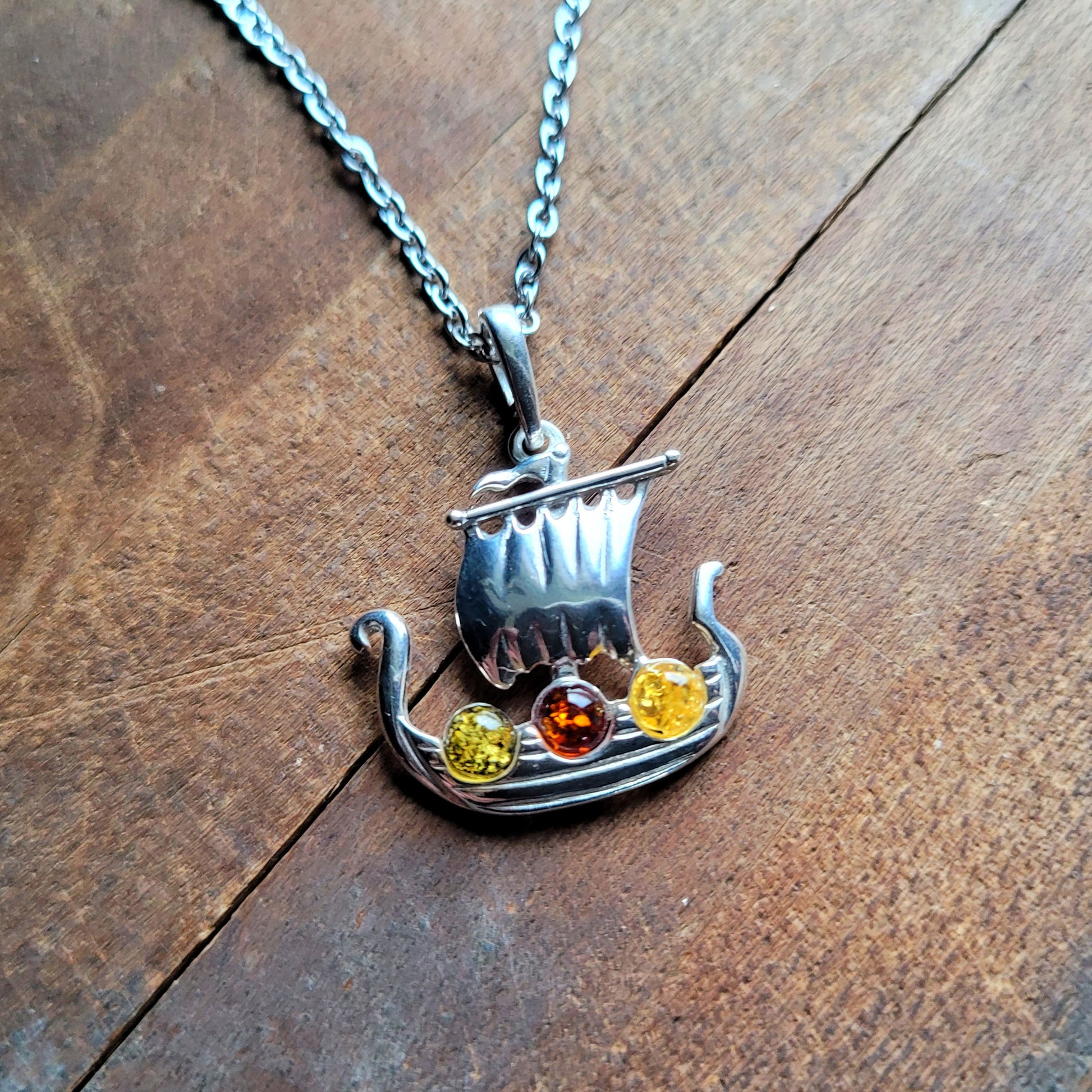 Longship pendant with green, gold, and cognac amber stones
